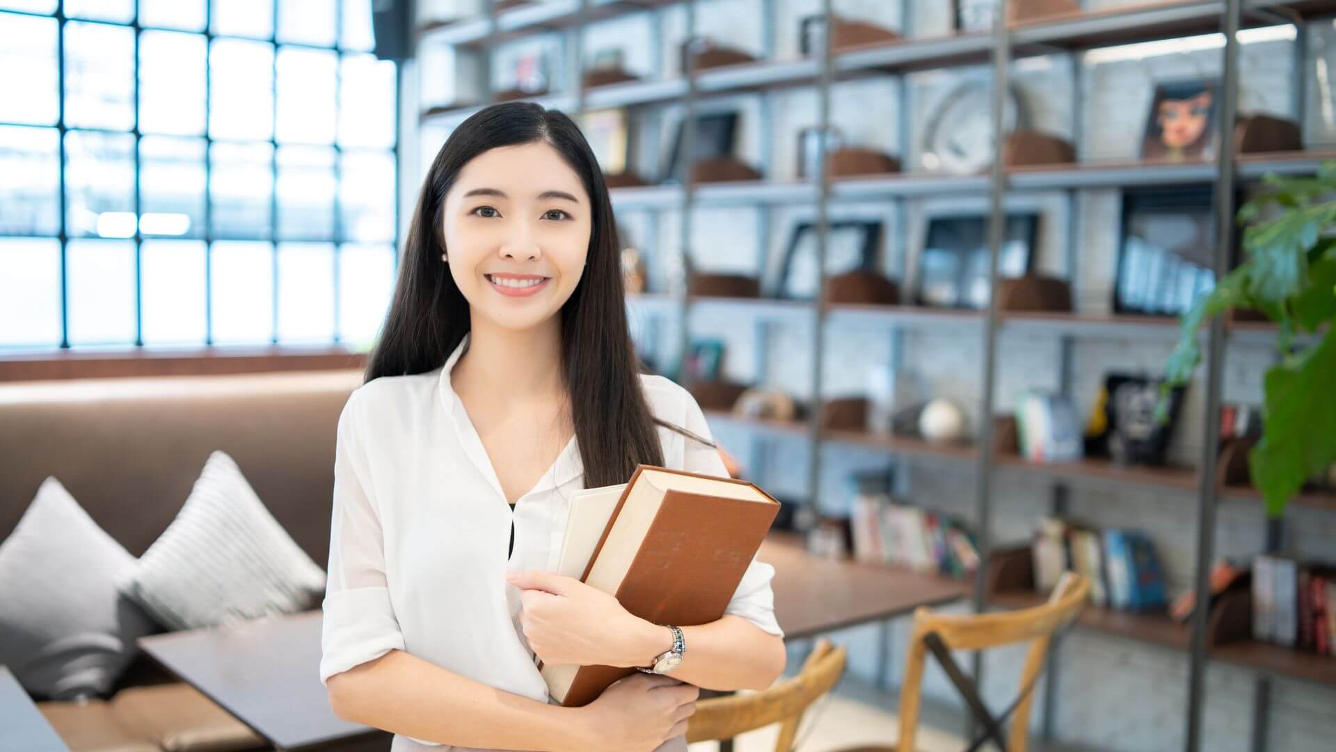 書籍を持って笑顔でこちらを向く中国人女性